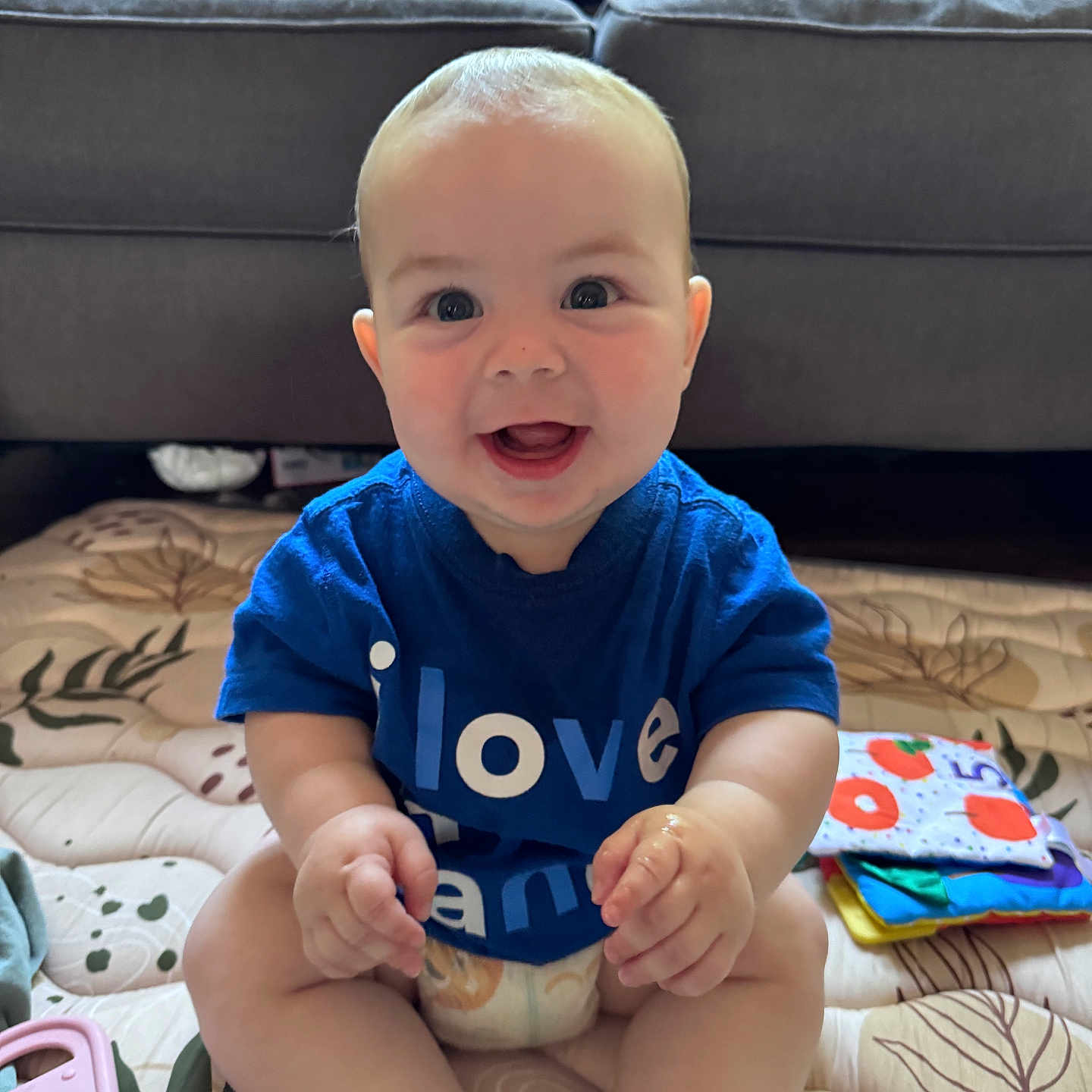 Copeland joined the competition — help win amazing prizes! baby, smiling, blue_shirt, sitting, toy, couch, indoor, happy, child, diaper, playmat, cute, infant, person, face, hands, feet, colorful, plush_toy, home