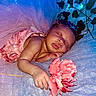 baby, blue_lighting, closeup, crown, cute, decorative_leaves, face, fairy_lights, flower, hand, indoors, infant, newborn, peaceful, pink_dress, portrait, resting, serene, sleeping, soft_fabric