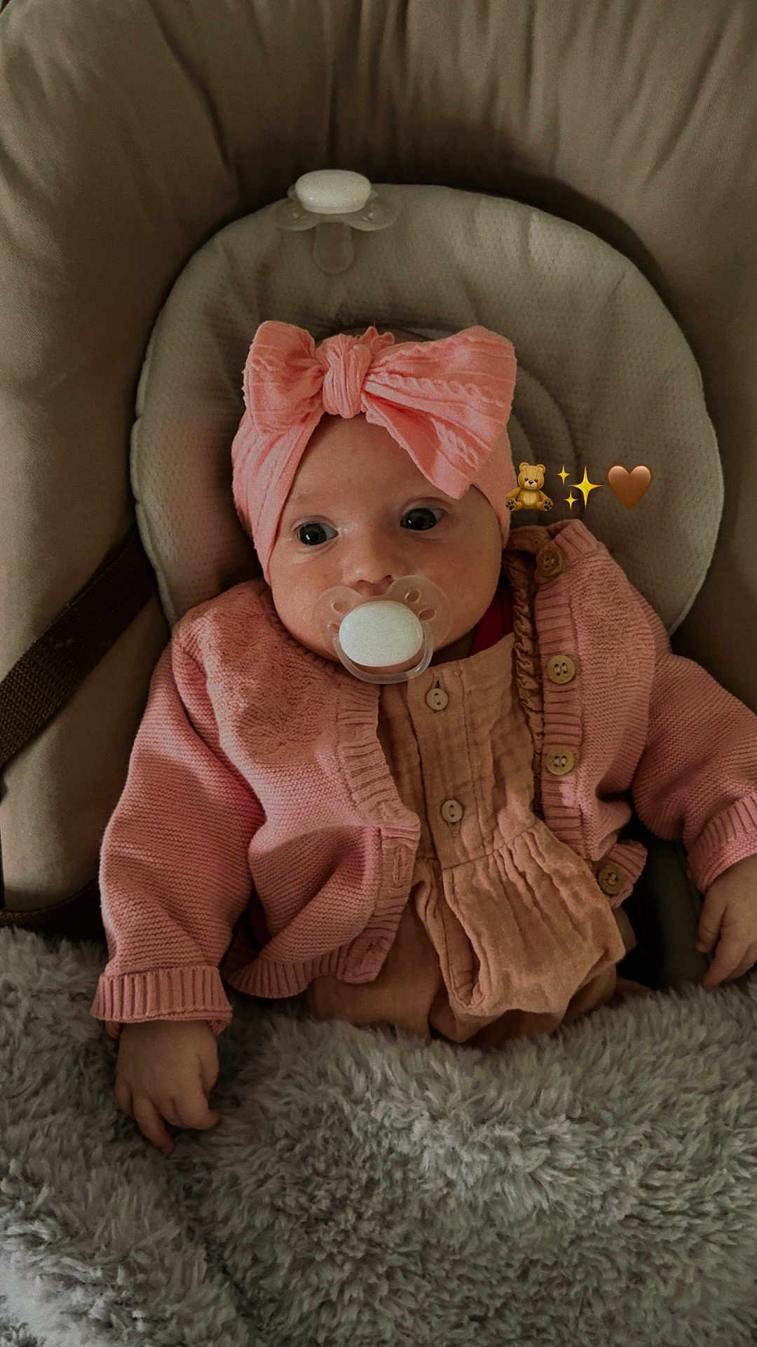 Nina participe au concours pour gagner de l'argent avec cette photo : baby, infant, pacifier, headband, pink_clothing, cardigan, blanket, seat, cushion, hand, cute, child, indoors, cozy, soft_texture, portrait, newborn, warm, comfortable, adorable