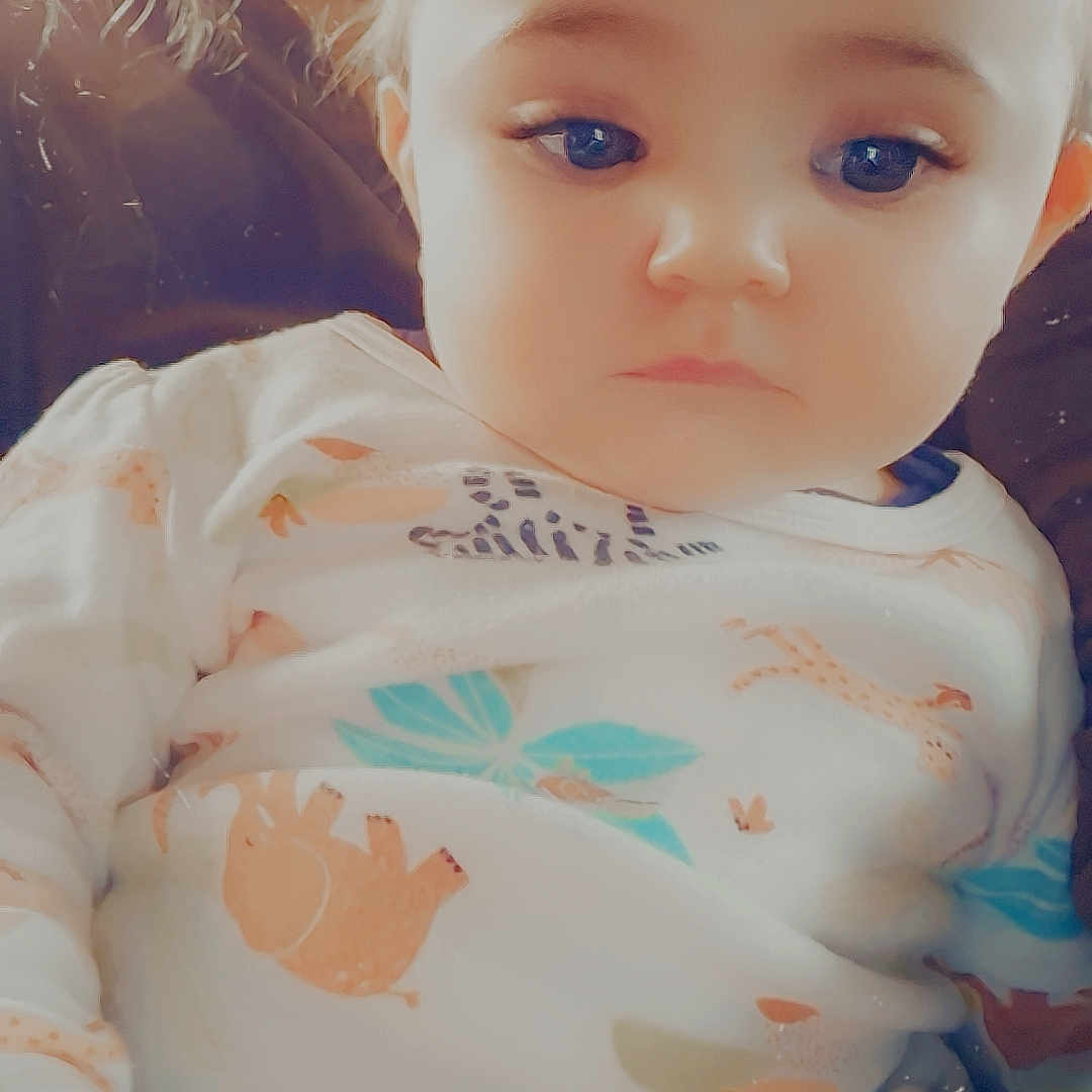 Ciara participe au concours pour gagner de l'argent avec cette photo : animal_print, baby, background_blur, child, clothing, cute, expressionless, eyes, face, hair, hand, indoor, lap, onesie, person, portrait, seated, skin, soft_light, young_child