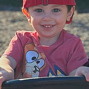 Sebastian joined the competition — help win amazing prizes! child, toddler, smiling, red_cap, cartoon_shirt, outdoor, playground, swing, happy, face, person, clothing, hat, sunlight, young_child, casual_wear, play, fun, daytime, cute