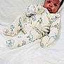 Jamal is registered to the contest to win money with this photo: baby, infant, dinosaur_print, onesie, blanket, soft_texture, cute, child, portrait, indoor, comfort, sleepwear, young, face, expression, cozy, resting, human, newborn, toddler