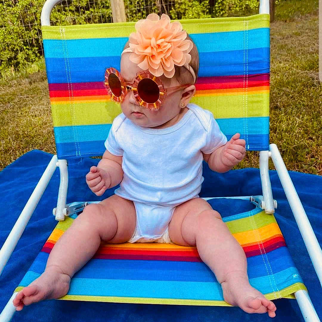 Alaina joined the competition — help win amazing prizes! accessories, baby, chair, clothing, diaper, face, furniture, glasses, grass, hat, head, outdoors, person, photography, plant, portrait, sitting, summer, sunglasses, swimwear