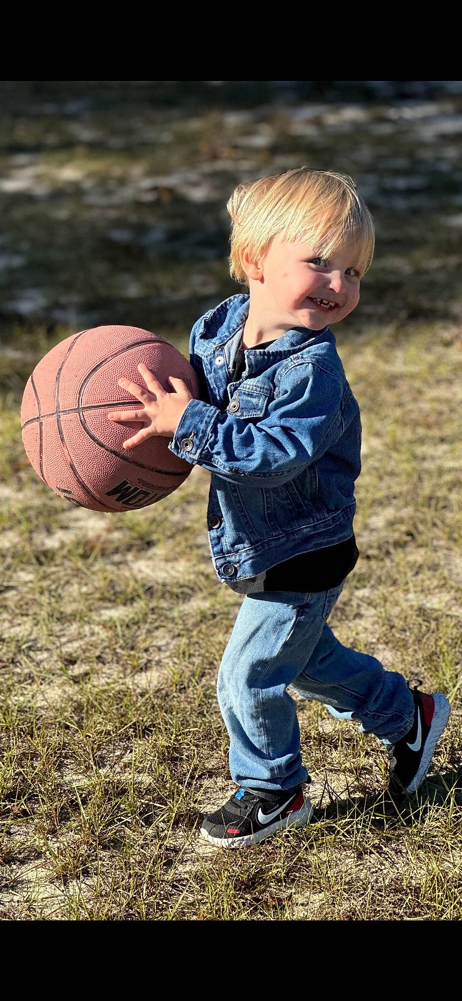 Carter joined the competition — help win amazing prizes! ball, ball_game, basketball, boot, child, fun, grass, happy, joy, leisure, people_in_nature, person, play, player, recreation, shorts, sitting, smile, sneakers, sports