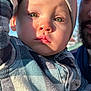 adult, baby, beanie, beard, child, closeup, cute, expressionless, face, green_eyes, hand, headwear, outdoor, person, plaid_shirt, portrait, shadow, sunlight, toddler, warm_light