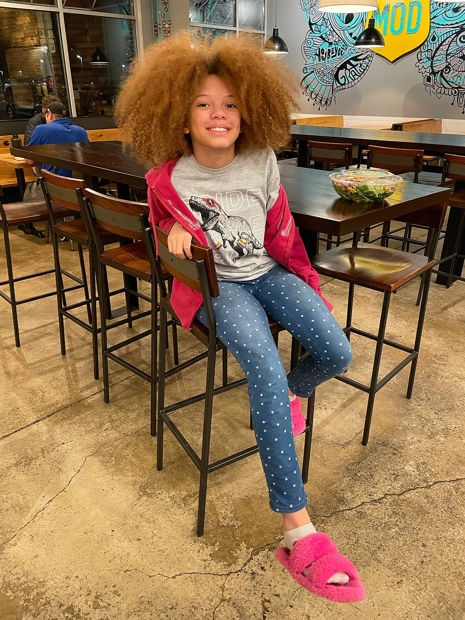 Allyssa is registered to the contest to win money with this photo: brown_hair, chair, denim, fashion_design, flooring, foot, fun, human_leg, jeans, joy, leg, leisure, person, room, sandal, shoe, sitting, smile, soil, table