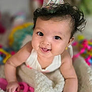 Emersyn is registered to the contest to win money with this photo: baby, party_hat, blanket, smiling, curly_hair, toy, colorful, indoor, closeup, infant, happy, cute, child, portrait, pink, white, soft_texture, celebration, young, person