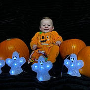 Elijah is registered to the contest to win money with this photo: baby, black_background, candy, celebration, child, costume, cute, decoration, festive, ghost_lights, glowing, halloween, happy, holiday, indoors, orange, pumpkin, pumpkin_costume, sitting, smile
