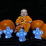 baby, black_background, candy, celebration, child, costume, cute, decoration, festive, ghost_lights, glowing, halloween, happy, holiday, indoors, orange, pumpkin, pumpkin_costume, sitting, smile