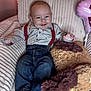 baby, infant, child, smiling, suspenders, striped_shirt, denim_jeans, stuffed_toy, balloon, armchair, corduroy, barefoot, cozy, indoor, portrait, happy_expression, rosy_cheeks, blue_eyes, soft_lighting, plush