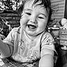 Quinn is registered to the contest to win money with this photo: baby, child, smile, happy, face, portrait, black_and_white, toddler, clothing, hair, toy, outdoor, blurred_background, arm, sitting, infant, expression, cute, closeup, person