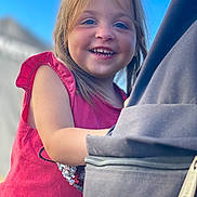 Léonie participe au concours pour gagner de l'argent avec cette photo : child, smiling, portrait, outdoor, blue_sky, red_dress, backpack, zipper, sequins, candid, happy, young_child, toddler, hair, teeth, close_up, sunlight, arm, sleeve, person
