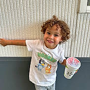 Lincoln joined the competition — help win amazing prizes! child, curly_hair, smiling, tshirt, shorts, drink, cup, straw, wall, texture, green_shoes, outdoor, happy, pose, person, casual_clothing, standing, cute, young, playful