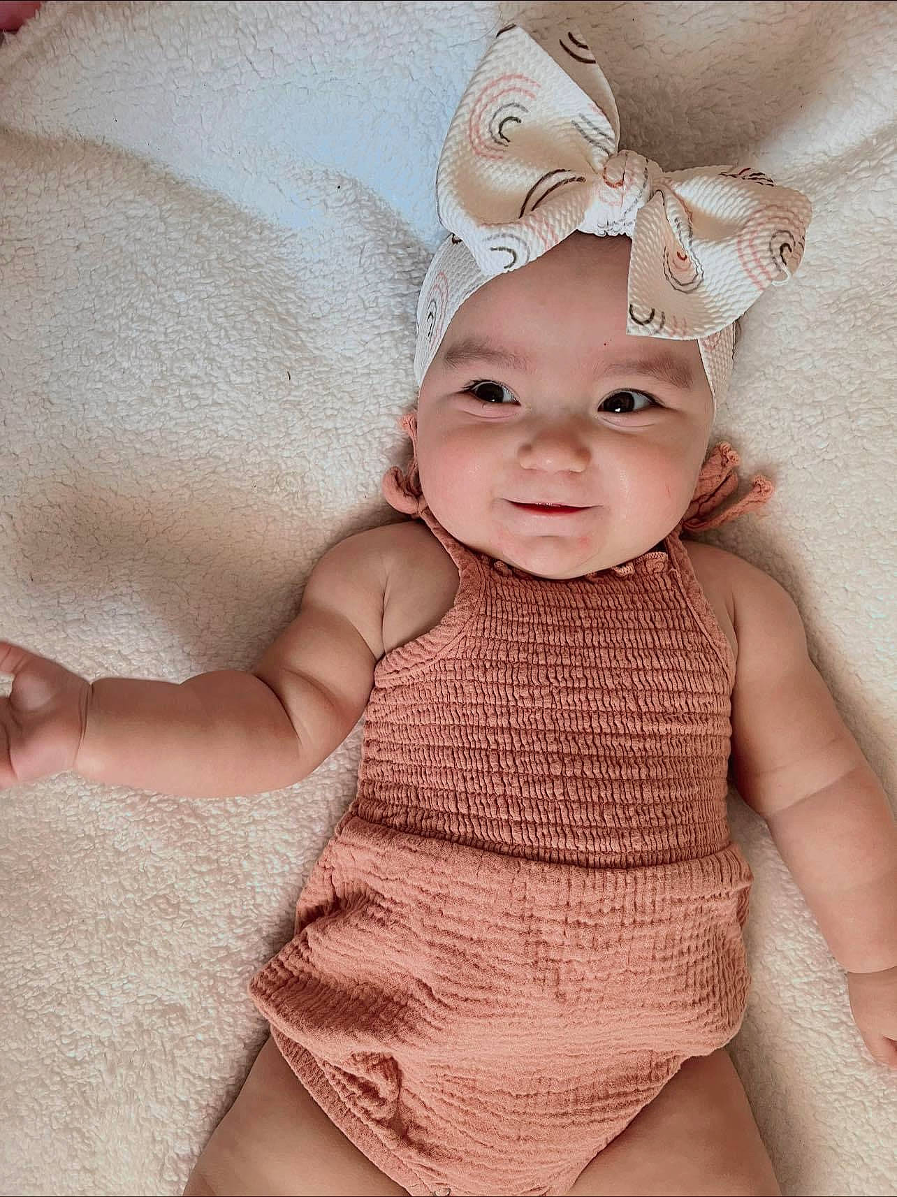 Bethany is registered to the contest to win money with this photo: baby, baby_toddler_clothing, cap, child, embellishment, fashion_accessory, hair_accessory, happy, headband, headgear, headpiece, headwear, human_leg, iris, magenta, pattern, person, skin, sleeve, smile