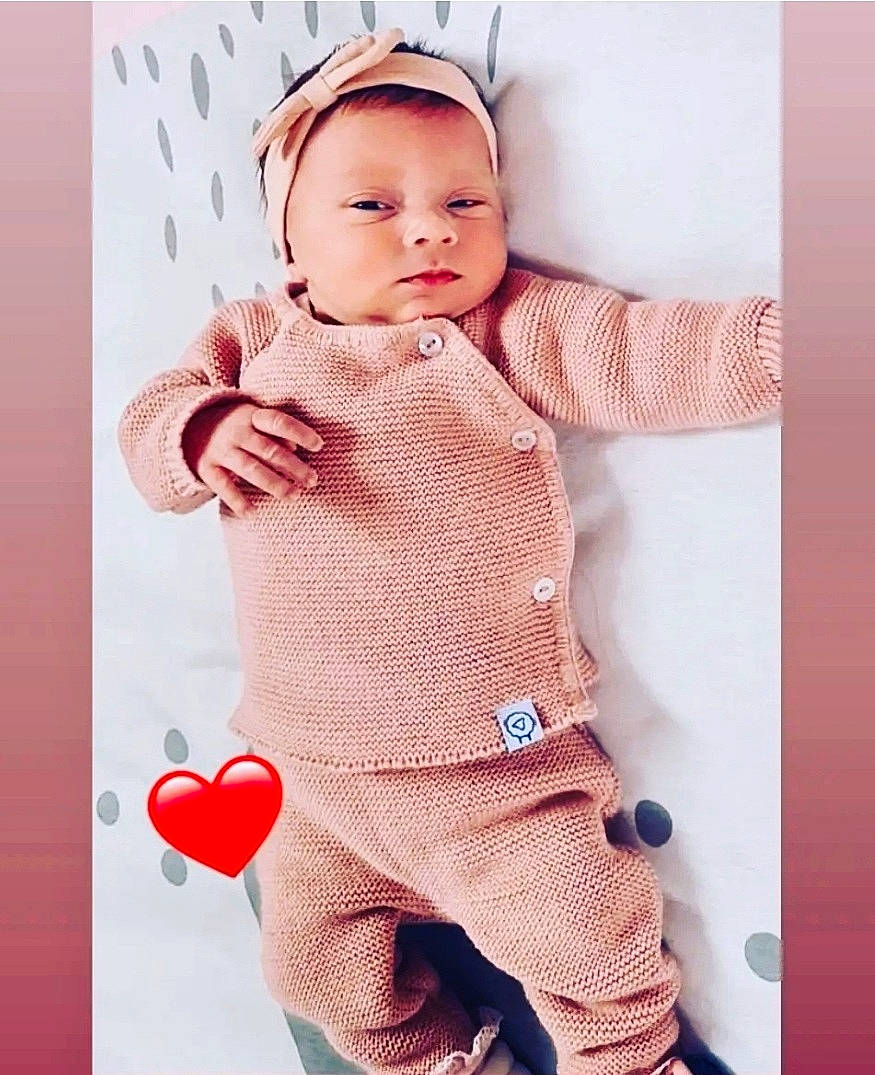 Lana participe au concours pour gagner de l'argent avec cette photo : arm, baby, baby_toddler_clothing, finger, gesture, happy, headwear, neck, outerwear, pattern, person, pink, product, skin, sleeve, standing, t_shirt, textile, thumb, toddler