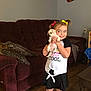 Ellie is registered to the contest to win money with this photo: black_and_white_clothing, chair, child, couch, dog, electric_outlet, framed_photo, girl, hair_bow, happy, indoor, living_room, person, pillow, puppy, smiling, table, toy_storage, water_bottle, wooden_floor