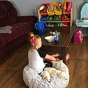 Ellie joined the competition — help win amazing prizes! blue_chair, bottle, bowl, child, coffee_table, floor, fluffy_cushion, furniture, hair_bows, home, indoor, living_room, maroon_couch, pink_backpack, puppies, relaxed, sitting, toy_organizer, white_puppies, wooden_floor