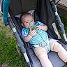 baby, bottle, stroller, grass, outdoor, child, onesie, infant, legs, feet, blue, black_socks, seatbelt, relaxing, sunlight, person, summer, casual, young, cute