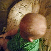 Clayton joined the competition — help win amazing prizes! baby, child, blurry, grainy, green_clothing, head, patterned_cushion, indoor, infant, sitting, top_view, soft_fabric, wearing_clothes, young_child, human, skin, small_child, person, cushion, blurred