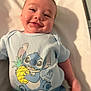 baby, child, smiling, blue_clothing, stitch_character, pineapple, infant, cute, happy, lying_down, shadow, indoors, short_hair, tshirt, playful, young_child, portrait, person, skin, face