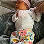 baby, infant, blanket, headband, floral_pants, white_socks, hand, person, sleeping, resting, soft_texture, indoor, cute, newborn, comfort, tenderness, clothing, portrait, lying_down, peaceful
