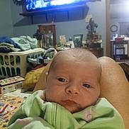 Rosa'Lli Benoit joined the competition — help win amazing prizes! baby, infant, blanket, legs, living_room, laundry_basket, television, furniture, person, clothing, home_interior, blanket_pattern, pink, green, face, eyes, table, decor, couch, relaxing