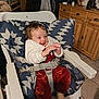 baby, child, high_chair, smiling, cozy_clothing, indoor, kitchen, wooden_cabinet, stone_wall, cushion, seat_belt, floor_tile, happy, person, infant, sitting, warm_lighting, red_pants, white_jacket, sock