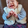 Elya a rejoint le concours — aidez-le/la à gagner de superbes lots ! baby, child, smiling, laughing, vest, plaid_skirt, gray_sleeves, hands, couch, seated, happy, cute, indoor, portrait, fuzzy, warm_clothing, infant, cozy, young, person