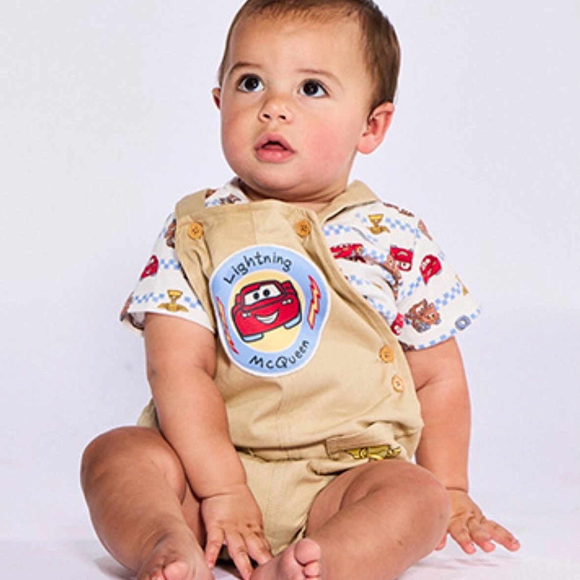 Jaxxton is registered to the contest to win money with this photo: toddler, child, baby, sitting, clothing, shorts, shirt, lightning_mcqueen, cartoon, cute, studio, portrait, barefoot, expression, face, hands, legs, footwear_free, curious, innocent