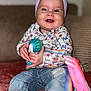 Andréa a rejoint le concours — aidez-le/la à gagner de superbes lots ! baby, bow, child, closeup, colorful, couch, denim, face, floral_clothing, hands, happy, headband, indoor, jeans, playful, rainbow, sitting, smiling, striped, toy