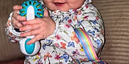 Andréa a rejoint le concours — aidez-le/la à gagner de superbes lots ! baby, casual, child, closeup, colorful, cute, floral_clothing, happy, headband, indoor, infant, jeans, person, pink_toy, playing, rainbow_strap, sitting, smiling, soft_furniture, toy