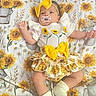 Ashly is registered to the contest to win money with this photo: baby, baby_clothing, blanket, bouquet, child, cute, dress, fashion, floral, headband, indoor, infant, lying_down, pacifier, portrait, smiling, socks, sunflower, textile, yellow_bow