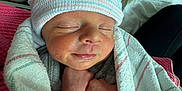 Michael is registered to the contest to win money with this photo: newborn, baby, infant, wrapped, blanket, hospital, hat, sleeping, peaceful, cute, skin, tiny_hands, person, portrait, closeup, indoors, comfort, rest, soft, cozy