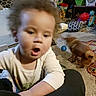Loki is registered to the contest to win money with this photo: child, toddler, baby, face, portrait, curious, surprised, open_mouth, indoor, home, living_room, dog, pet, toys, carpet, couch, seated, casual_clothing, blond_hair, photograph
