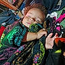 Loki is registered to the contest to win money with this photo: baby, sleeping, infant, portrait, crocheted_blanket, colorful_blanket, curly_hair, closed_eyes, peaceful, cozy, indoors, bed, clothing, hand, arm, textile, household, laundry, power_strip, closeup