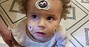 Loki joined the competition — help win amazing prizes! baby, child, curly_hair, sticker, spider, face, portrait, looking_up, indoor, tile_floor, patterned_floor, infant, clothing, shirt, pants, adult_hand, sitting, curious, closeup, photography