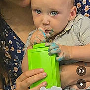 Jerico is registered to the contest to win money with this photo: adult_hand, baby, birthday_candles, blue_paint, celebration, child, closeup, clothing, curious, face, finger_in_mouth, floral_pattern, glasses, green_container, hands, indoor, paint, party, person, table