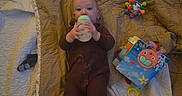 Jerico is registered to the contest to win money with this photo: baby, blanket, bottle, child, colorful, comfort, cute, feeding, floor, indoor, infant, lying_down, onesie, person, play, quilt, resting, soft_lighting, toy, young