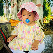 Aira joined the competition — help win amazing prizes! toddler, child, pacifier, hat, bucket_hat, dress, floral_dress, white_socks, tree, outdoor, handbag, sitting, cute, young_child, portrait, daylight, nature, skin, face, clothing