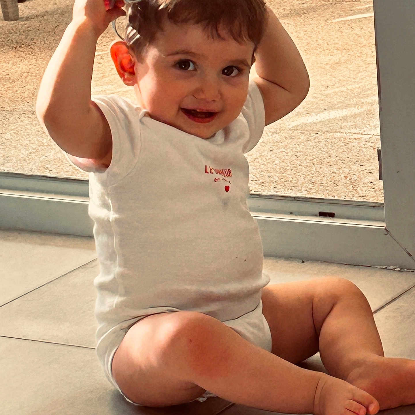 Lino participe au concours pour gagner de l'argent avec cette photo : baby, barefoot, child, cute, expression, floor, happy, head, indoor, legs, natural_light, person, playful, skin, smile, sunglasses, toddler, white_clothing, window, young_child