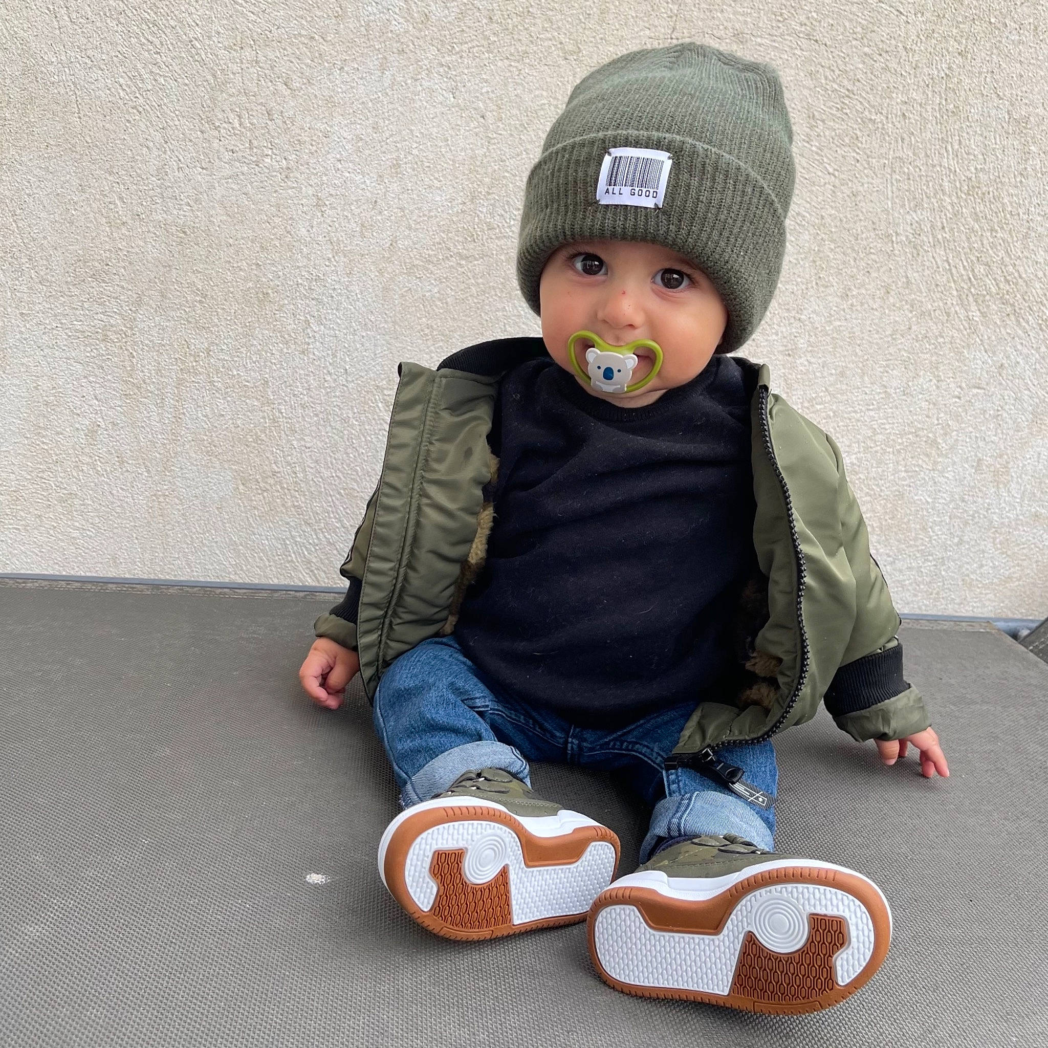 Maylann a rejoint le concours — aidez-le/la à gagner de superbes lots ! baby, baby_products, baby_toddler_clothing, baby_toddler_shoe, beanie, beige, bonnet, cap, headwear, knit_cap, person, sitting, slipper, toddler, walking_shoe, wool, woolen