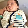 Haroun participe au concours pour gagner de l'argent avec cette photo : baby, child, infant, onesie, striped_clothing, whale, crab, hand, pacifier, blue, white, sleepy, person, indoor, relaxing, cute, soft_focus, closeup, portrait, calm