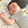 baby, sleeping, infant, striped_clothing, onesie, yellow, blanket, pattern, triangle_pattern, peaceful, cute, soft_light, indoors, closeup, child, resting, portrait, pale_skin, dark_hair, small_hand