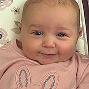Maura joined the competition — help win amazing prizes! baby, infant, smile, face, pink_clothing, bunny_design, cushion, floral_pattern, cute, child, portrait, closeup, happy, indoors, person, head, cheeks, eyes, baby_girl, soft_lighting