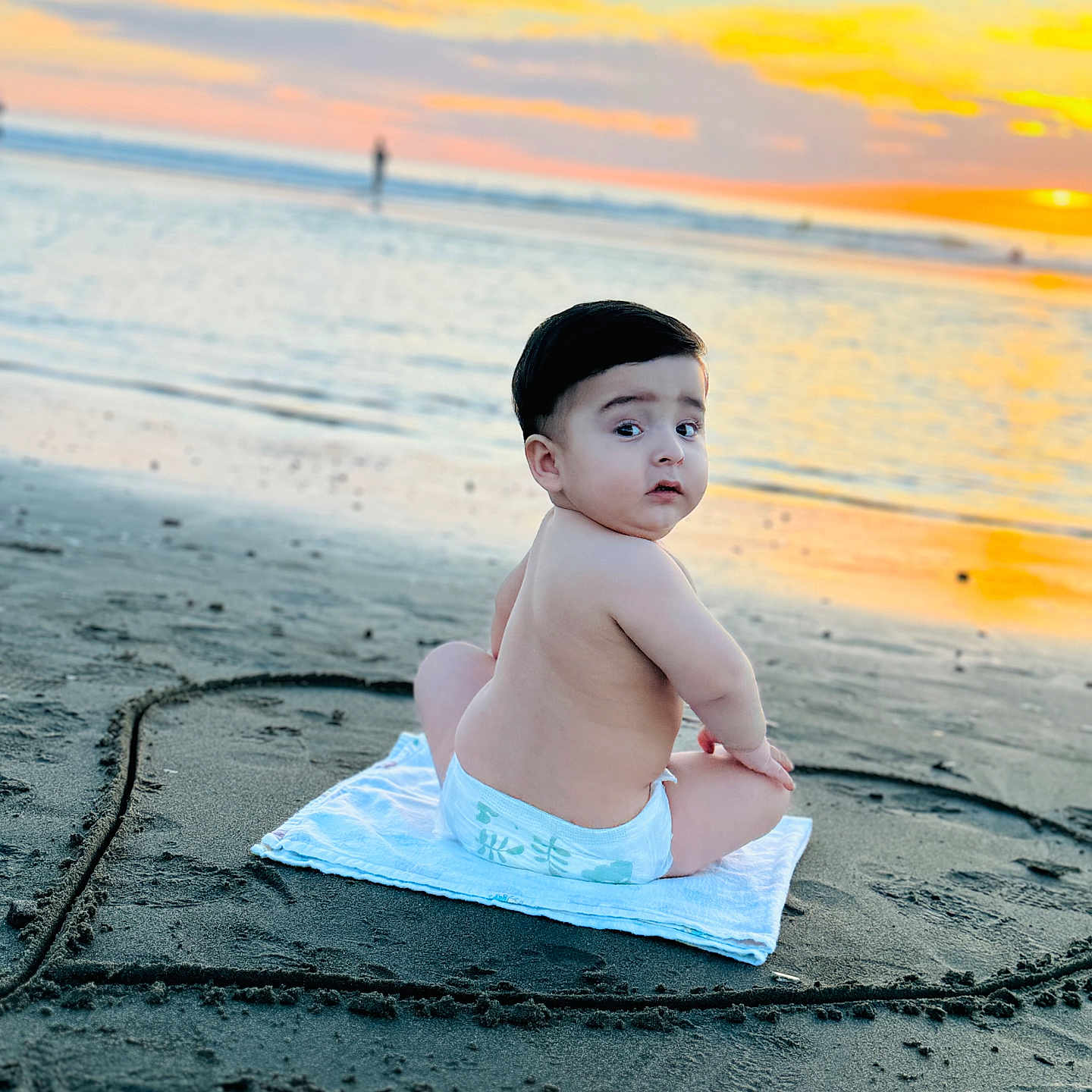 Hamza is registered to the contest to win money with this photo: baby, beach, child, clouds, cute, diaper, heart_shape, horizon, infant, nature, ocean, outdoor, person, sand, sitting, sky, sun, sunset, towel, water