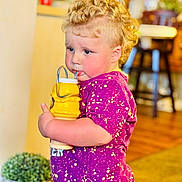 Noah joined the competition — help win amazing prizes! toddler, child, curly_hair, purple_shirt, yellow_cup, indoor, plant, wooden_floor, furniture, drinking, cute, person, face, diaper, home, casual, colorful, young_child, blonde_hair, standing