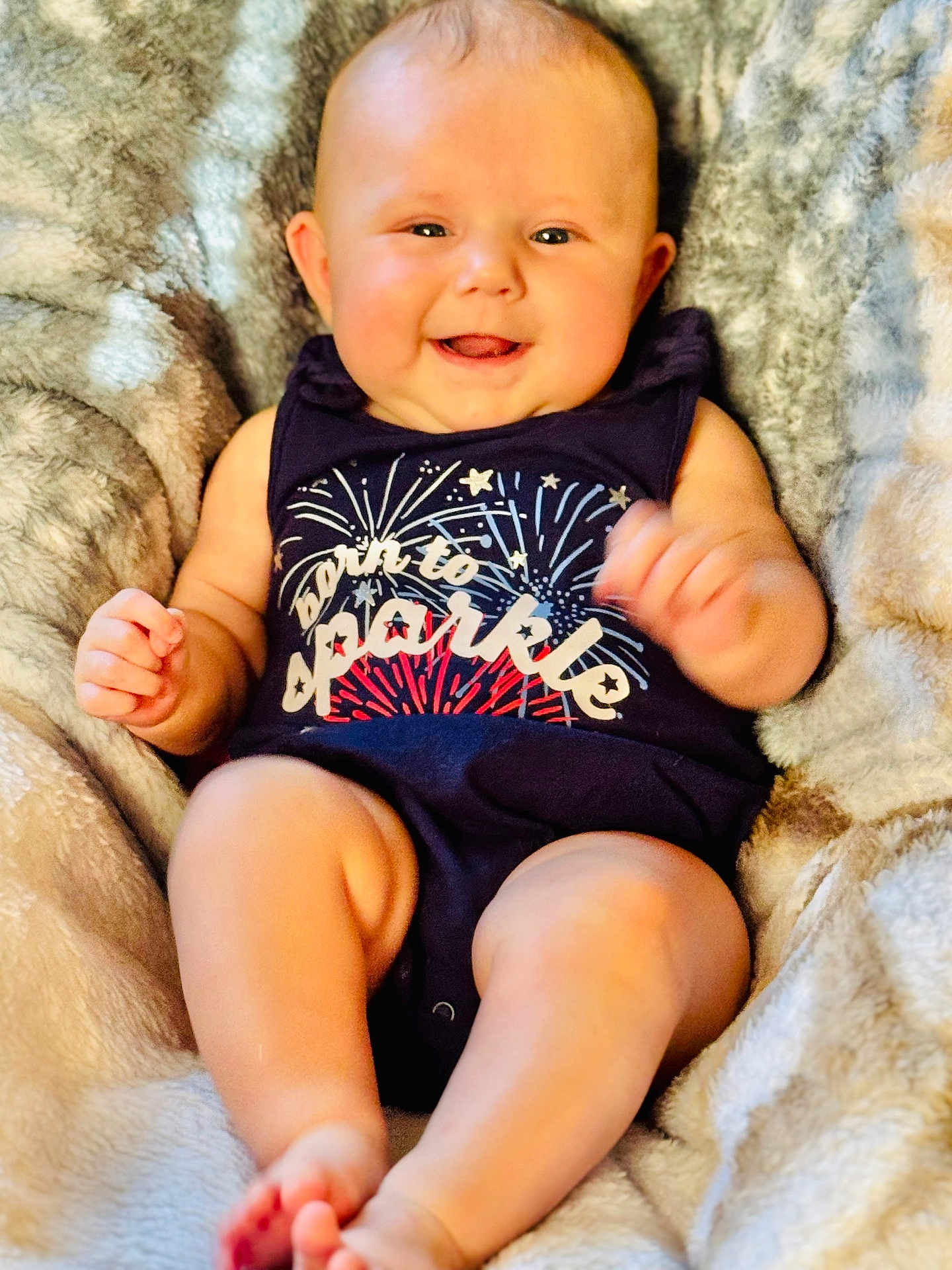 Lauren joined the competition — help win amazing prizes! baby, infant, smiling, onesie, clothing, fireworks, blanket, soft, cute, happy, chubby_cheeks, face, skin, person, portrait, sitting, cozy, indoor, child, newborn