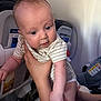 baby, infant, child, airplane, seat, hand, striped_clothing, person, interior, travel, transportation, car_seat, safety_card, curious, blue_eyes, holding, human, cabin, closeup, cute
