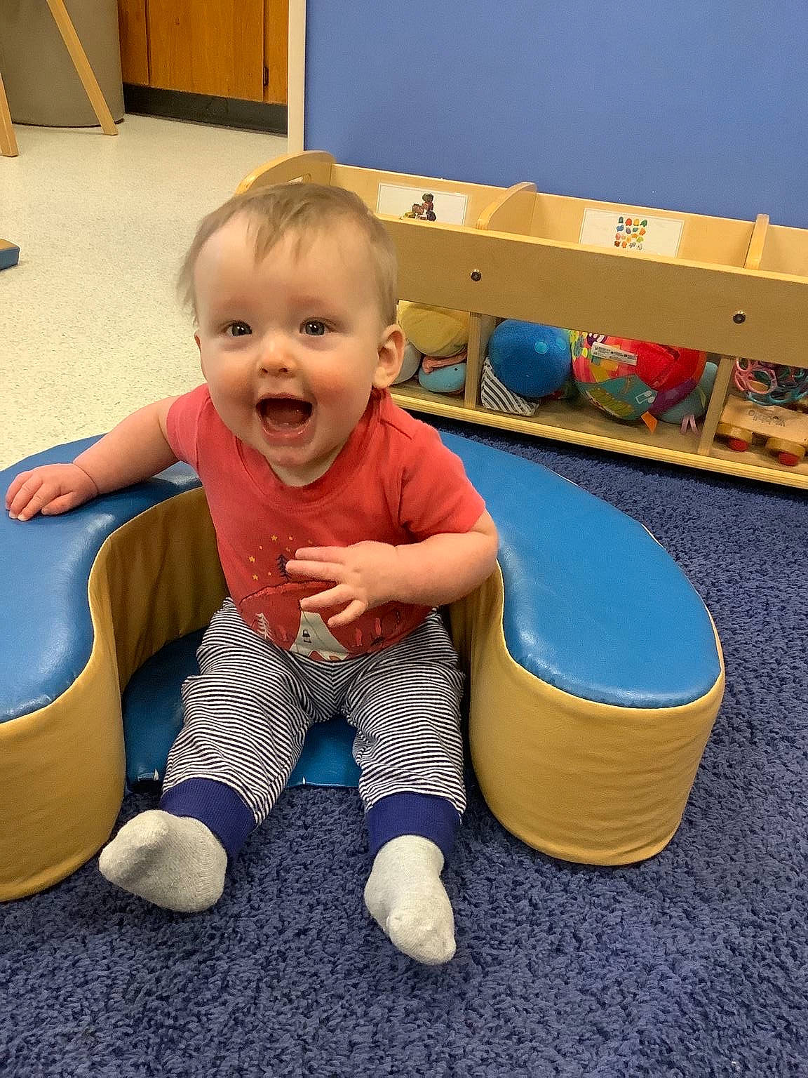 Gregory joined the competition — help win amazing prizes! baby, baby_playing_with_toys, baby_toddler_clothing, child, comfort, electric_blue, facial_expression, floor, flooring, fun, happy, knee, person, play, room, sitting, smile, sock, t_shirt, toddler