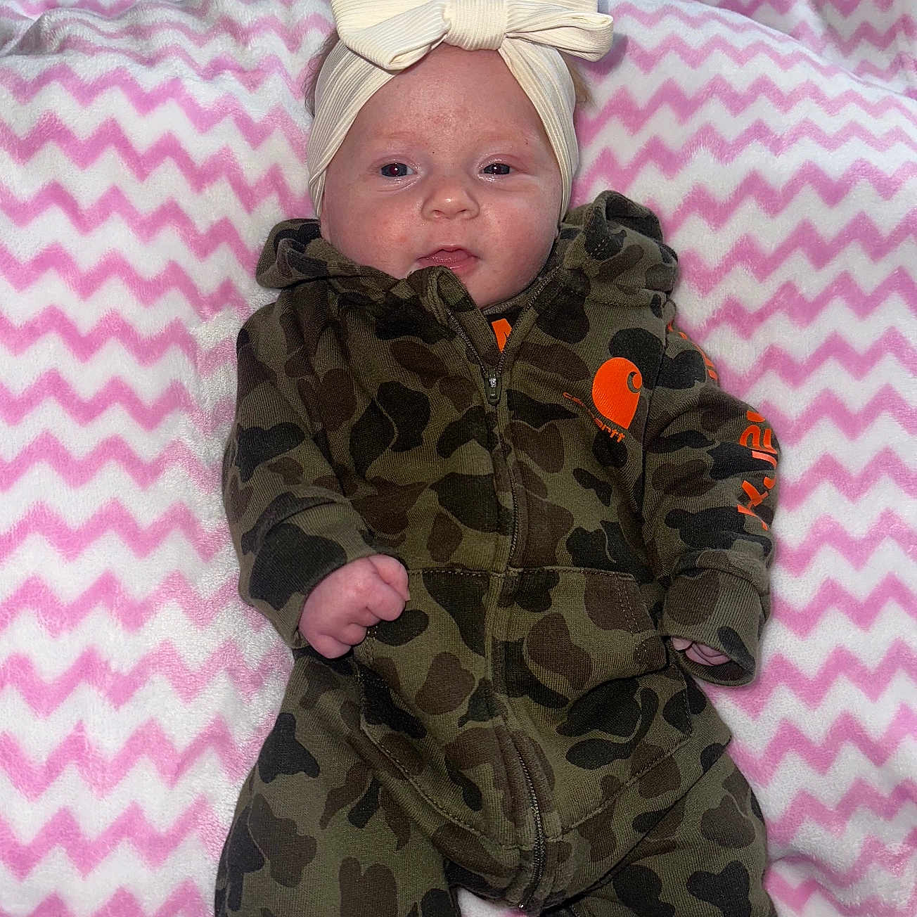 Izabella joined the competition — help win amazing prizes! baby, blanket, bow, camo_clothing, child, clothing, cute, face, headband, indoor, infant, lying_down, onesie, person, pink, portrait, soft_texture, white, young, zigzag_pattern